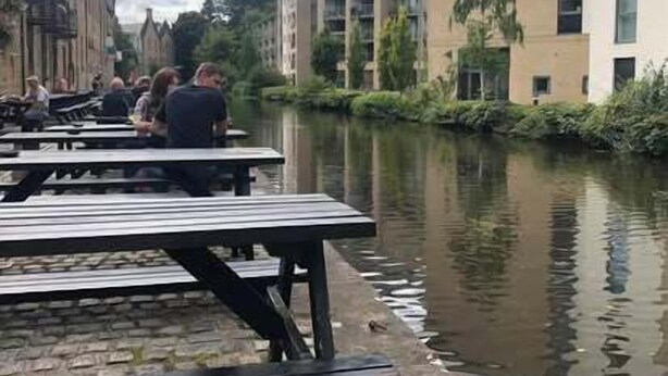 Buitenplaatsen aan een gracht met gebouwen op de achtergrond.