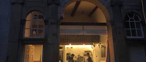 A historic building with a large arched entrance, a visible interior with tables and chairs, and a sign indicating a music room.