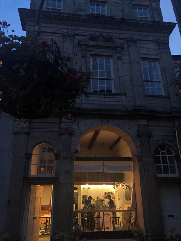 A historic building with a large arched entrance, a visible interior with tables and chairs, and a sign indicating a music room. - The Joseph Cosy at Lancaster (Lancaster)