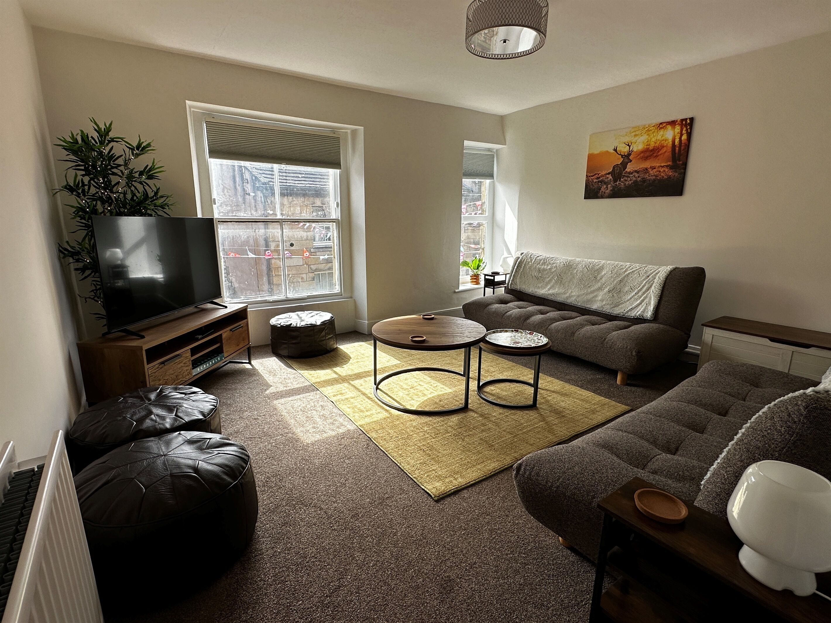 A living room with a TV, sofa, coffee table, and a painting on the wall.