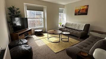 A living room with a TV, sofa, coffee table, and a painting on the wall.