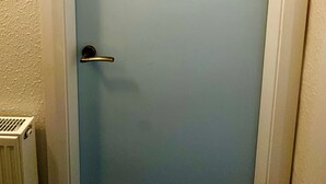 Une porte avec un panneau bleu clair, une poignée en métal et deux icônes noires représentant des toilettes pour hommes et pour femmes.