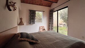 A bedroom with a large bed, a window with curtains, a brick ceiling, and a view of greenery outside. - Casa Tacuba country house near the mountain and lake Chapala (San Juan Cosalá)