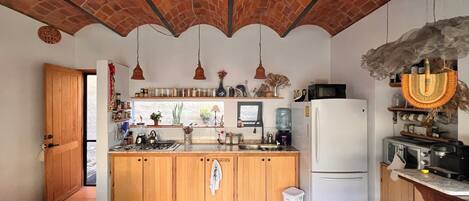 A kitchen with wooden cabinets, a refrigerator, a stove, and hanging pendant lights.