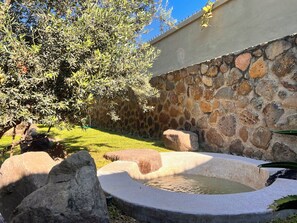 A stone wall, a circular water feature, and a tree.