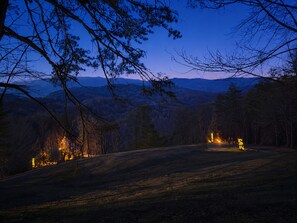 A nighttime landscape with a road, trees, and distant mountains.
