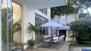 Eine Terrasse mit Tisch und Stühlen, einem Grill und einem Swimmingpool.