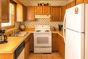 A kitchen with wooden cabinets, a stove, a sink, and a refrigerator. - Mountain Ridge-VIEWS-Pigeon Forge | Hot Tub, Decks & Fireplace | Sleeps 4 (Pigeon Forge)