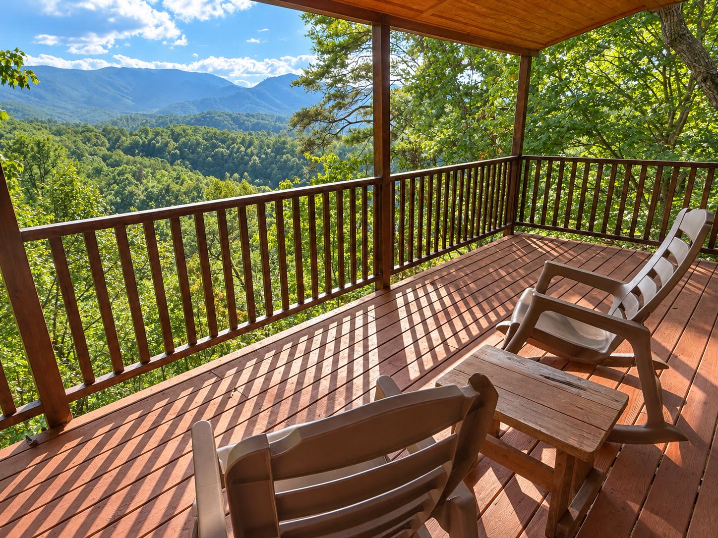 A wooden deck with a view of a forested valley and mountains.