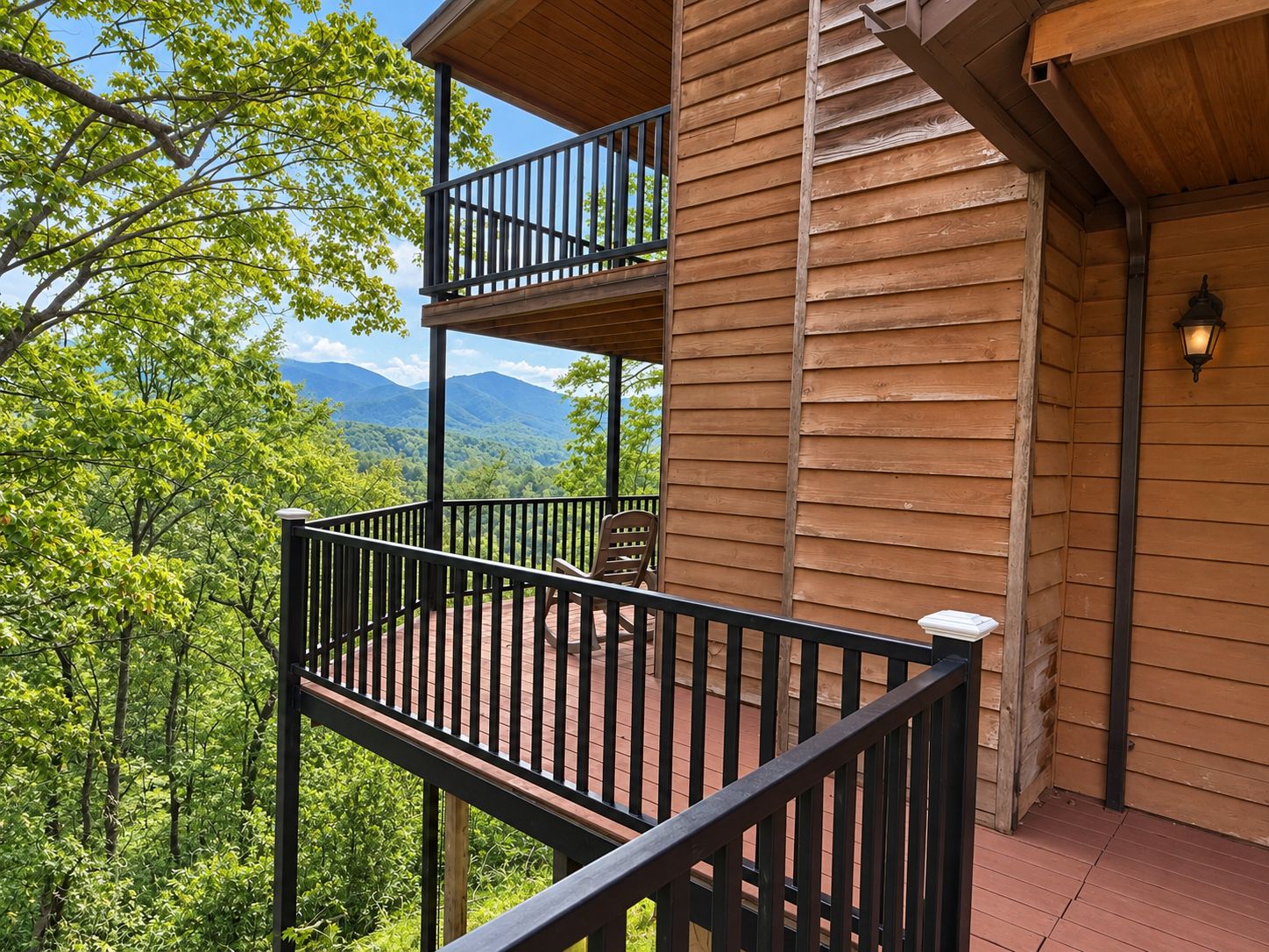 A wooden cabin with a balcony overlooking a forested mountain range.