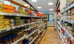 Ein Gang in einem Supermarkt mit verschiedenen verpackten Lebensmitteln und einem Kühlregal im Hintergrund.