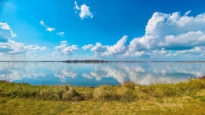 Ein ruhiger See mit klarer Spiegelung des Himmels und der Wolken, umgeben von grasbewachsenen Ufern.
