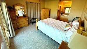 Une chambre à coucher comprenant un lit, une commode, un miroir et un ventilateur de plafond.