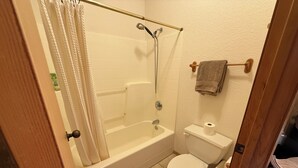 Une salle de bain avec une baignoire, des toilettes et un rideau de douche.