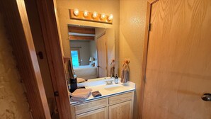 Une salle de bain avec un meuble-lavabo en bois, un miroir, un lavabo et un porte-serviettes.