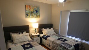 A room with two beds, a nightstand, a lamp, a window with blinds, and a colorful abstract painting on the wall. - 2 Bedroom, 2 Bath, Mobile Home, Great Location in Athens, Steps To Bike Path (Athens)
