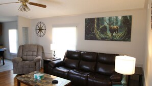 A living room with a leather sofa, a coffee table, a ceiling fan, a painting of a deer, and a compass wall decoration. - 2 Bedroom, 2 Bath, Mobile Home, Great Location in Athens, Steps To Bike Path (Athens)