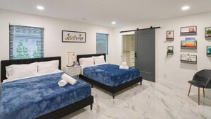 A hotel room with two beds, a chair, a wardrobe, and a bathroom. - Peaceful Villa by Glam Homes (Hollywood)