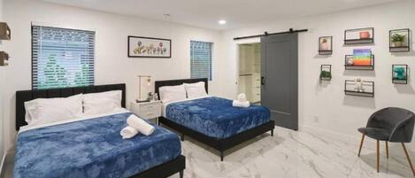 Habitación de hotel con dos camas, una silla, un armario y un baño.