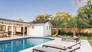 A residential property with a swimming pool, outdoor seating, and a covered patio area. - Peaceful Villa by Glam Homes (Hollywood)