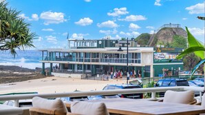 En restaurang vid stranden med uteservering, utsikt över havet och en skylt som visar vägen till Curubin Beach Vikings.