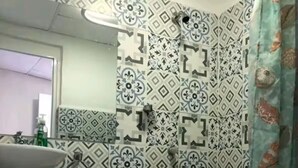 Ein Badezimmer mit gemusterten Fliesen, einem Waschbecken auf Säule und einer Duschvorhang.