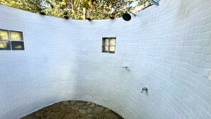 A white-tiled room with a curved wall, a small window, and a showerhead. - Koro Island Resorts Fiji (Koro Island)