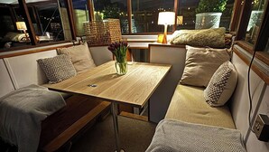 A cozy interior with a wooden table, cushioned seating, and a vase of flowers. - Unique 2 Bed Waterside Retreat, Pet Friendly (Worcester)