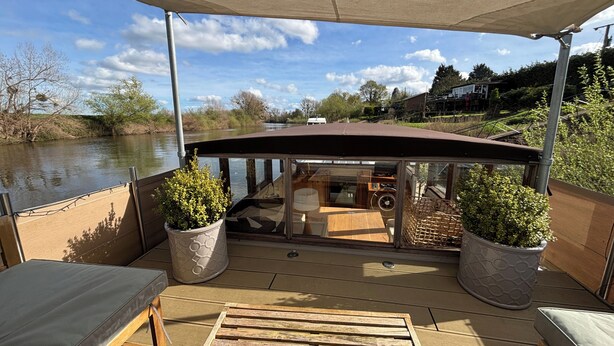 A covered outdoor deck with a view of a river, wooden furniture, and potted plants. - Unique 2 Bed Waterside Retreat, Pet Friendly (Worcester)