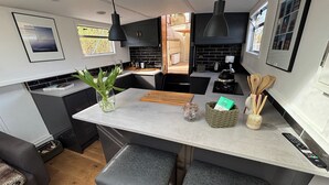 A modern kitchen with a central island, black cabinets, and a view into the dining area. - Unique 2 Bed Waterside Retreat, Pet Friendly (Worcester)