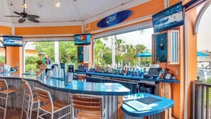 A bar area with a counter, bar stools, a ceiling fan, and a television screen. - Bahama Bay 515 Rum run unit 515  (Davenport)