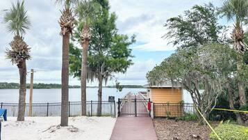 A pathway leading to a beach area with palm trees, a wooden structure, and a view of the water.