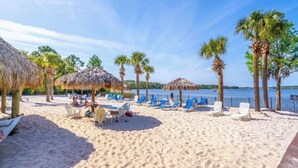 A beach with thatched umbrellas, palm trees, and lounge chairs. - Bahama Bay 515 Rum run unit 515  (Davenport)