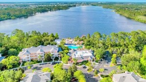 A resort with a swimming pool, surrounded by lush greenery and a large body of water. - Bahama Bay 515 Rum run unit 515  (Davenport)