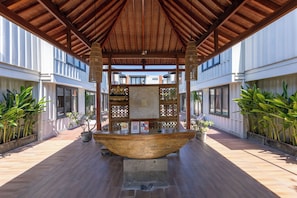 A covered outdoor area with a wooden structure, potted plants, and a reception desk. - Allende Canggu (Canggu)