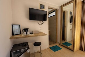 A room with a flat-screen TV mounted on the wall, a small desk with a computer, a coffee maker, and a framed certificate on the wall. - Allende Canggu (Canggu)