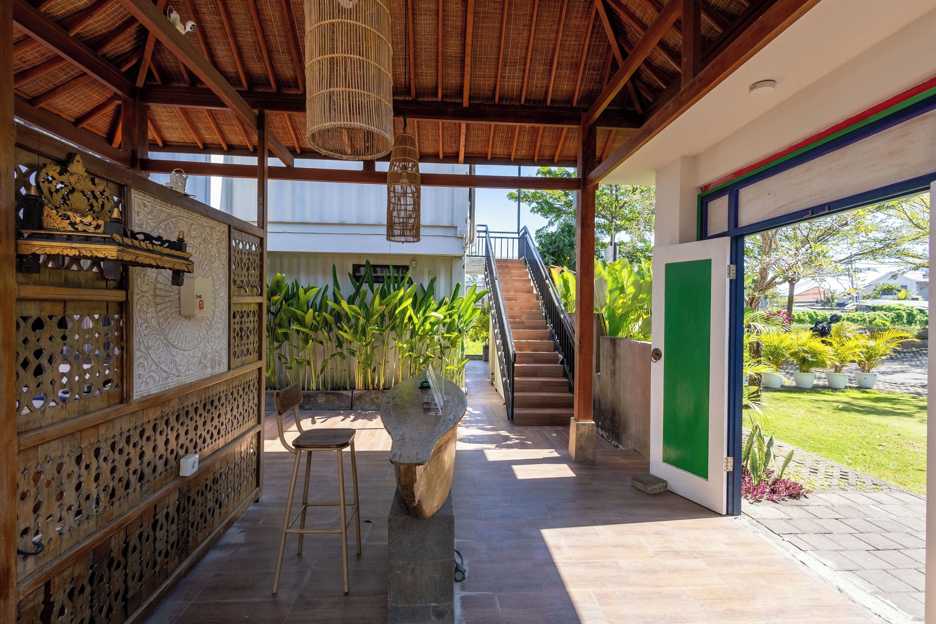 Un espacio al aire libre cubierto con techo de madera, un banco de piedra y una escalera que lleva a un edificio.