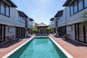 A modern hotel with a central swimming pool, large windows, and a covered seating area. - Allende Canggu (Canggu)