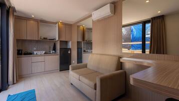 Cocina pequeña con electrodomésticos integrados, un sofá y una ventana con cortinas.