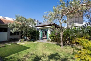 A residential property with a well-maintained lawn, a green door, and a variety of plants. - Allende Canggu (Canggu)
