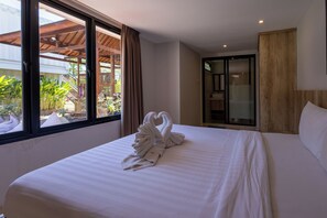 A hotel room with a bed, a window with curtains, a view of the outdoors, and a bathroom with a glass door. - Allende Canggu (Canggu)