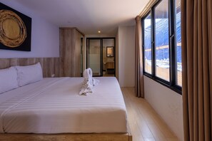 A hotel room with a large bed, a bathroom with a glass door, and a view of a snowy landscape. - Allende Canggu (Canggu)
