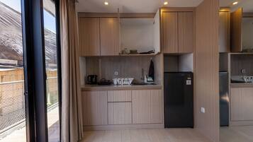 Una cocina moderna con armarios de madera, un refrigerador negro y una ventana con cortinas.