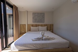 A hotel room with a large bed, a wooden headboard, a wall-mounted artwork, and a sliding glass door. - Allende Canggu (Canggu)