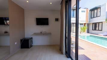 Una sala de estar moderna con un televisor de pantalla plana montado en la pared, una mesita con una caja de pañuelos y un calentador portátil negro sobre el suelo.