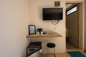 A small room with a television mounted on the wall, a framed certificate on a shelf, a kettle, a box, and a stool. - Allende Canggu (Canggu)