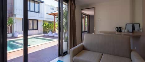 Una sala moderna con un sofá, una mesa de centro y vista a una piscina al aire libre.