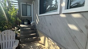 Ein Haus mit überdachter Veranda, einem weißen Stuhl und einem kleinen Hund.
