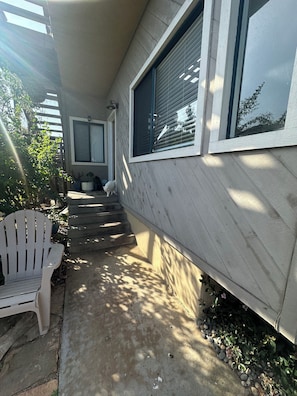 Ein Haus mit überdachter Veranda, einem weißen Stuhl und einem kleinen Hund.