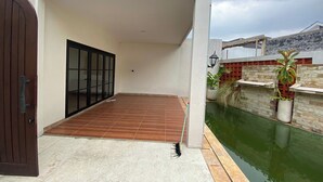 A modern house with a wooden deck, a gated entrance, and a small water feature. - D'Jiwa by Semesta Management (Turi)
